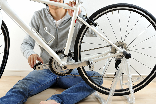 ロードバイクをメンテナンスする男性